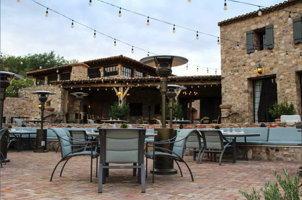 Outdoor dining terrace with string lights at a stone estate